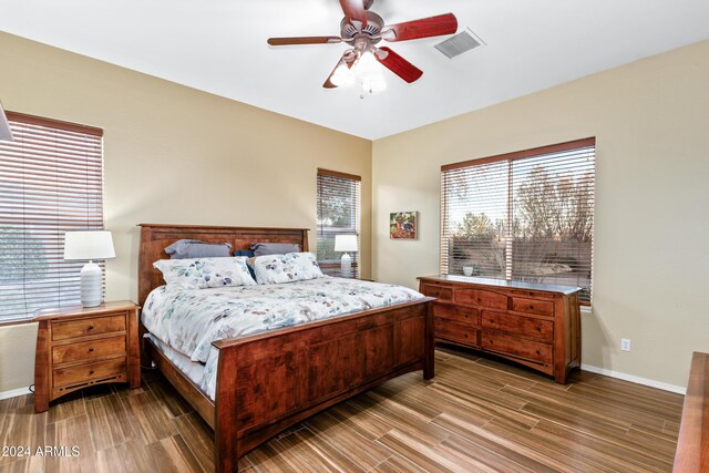 bedroom with multiple windows, wood-type flooring, and ceiling fan