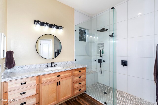 bathroom featuring tiled shower, vanity, and hardwood / wood-style flooring