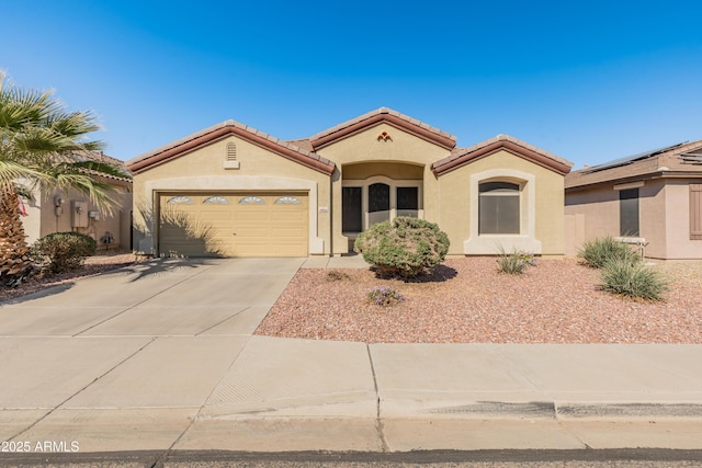 mediterranean / spanish home with concrete driveway, a tiled roof, an attached garage, and stucco siding