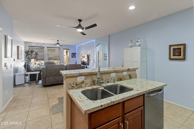 kitchen with a center island with sink, brown cabinets, open floor plan, a sink, and stainless steel dishwasher