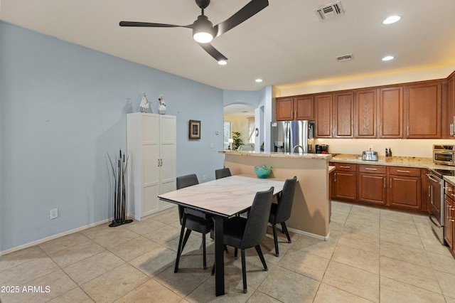 kitchen featuring brown cabinets, visible vents, stainless steel appliances, and arched walkways