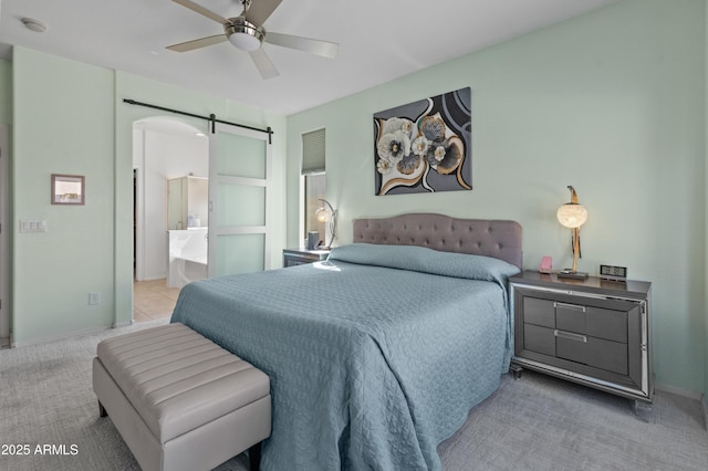 carpeted bedroom with ensuite bathroom, ceiling fan, and a barn door