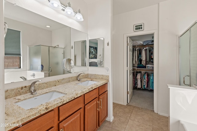 bathroom featuring double vanity, a shower stall, a spacious closet, and a sink