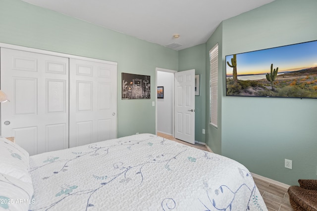 bedroom with wood tiled floor, baseboards, and a closet