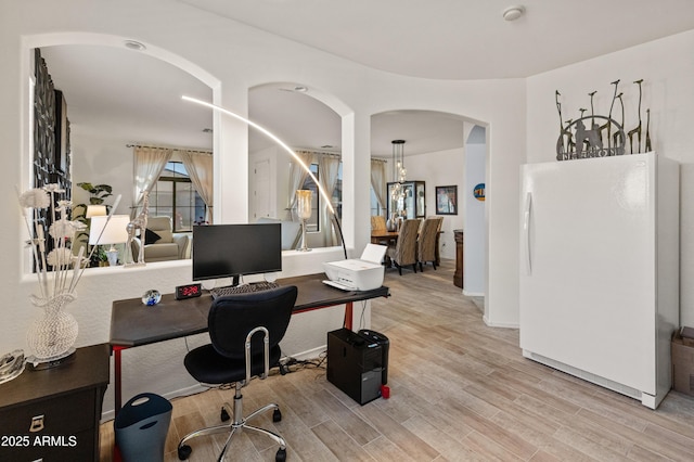 office featuring light wood-type flooring and arched walkways