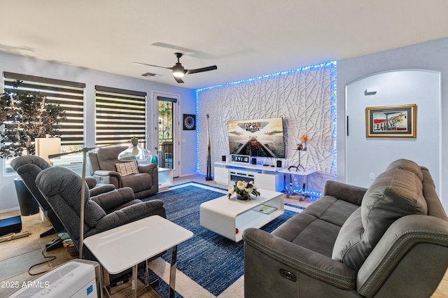 living room featuring arched walkways, ceiling fan, and visible vents