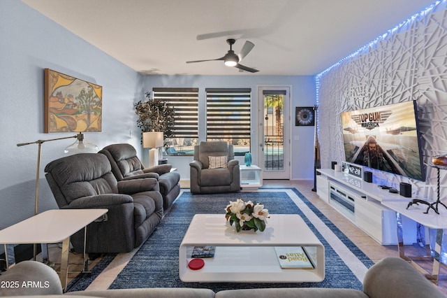 living room featuring an accent wall, ceiling fan, and baseboards