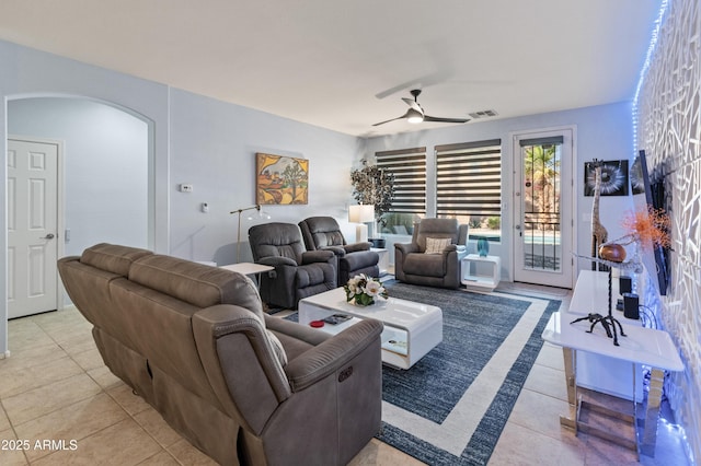 living area with arched walkways, light tile patterned floors, visible vents, and a ceiling fan