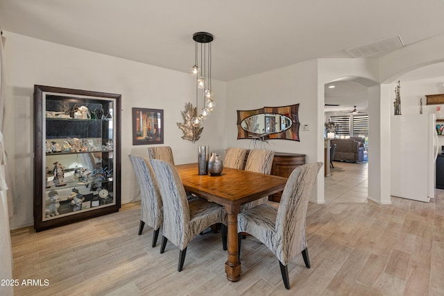 dining room with light wood-type flooring, visible vents, and arched walkways