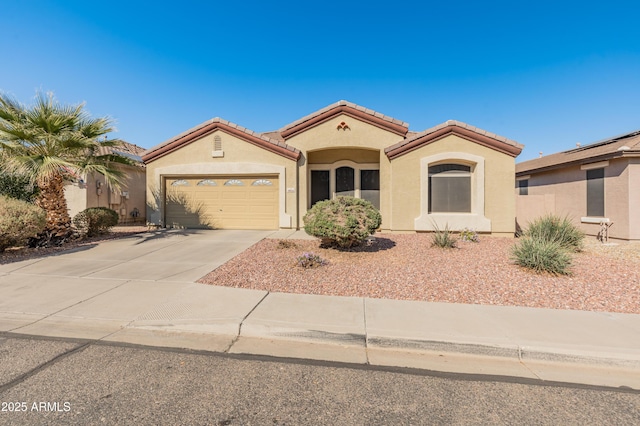 mediterranean / spanish home with an attached garage, a tiled roof, concrete driveway, and stucco siding