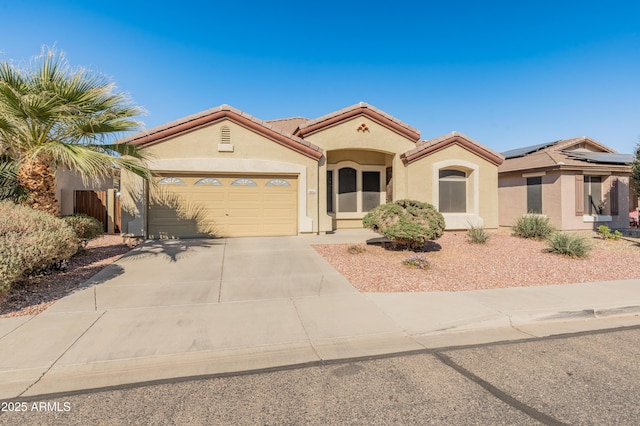 mediterranean / spanish house featuring a garage, concrete driveway, a tile roof, and stucco siding