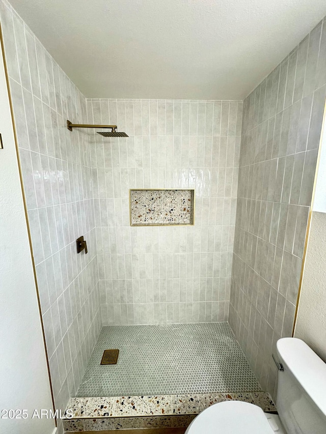 full bathroom featuring toilet and tiled shower