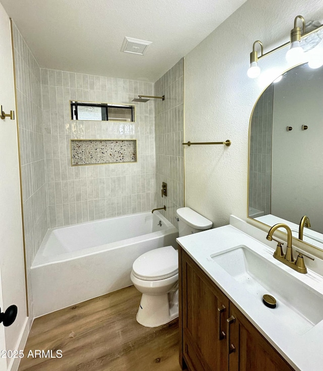 bathroom featuring vanity, toilet, bathing tub / shower combination, wood finished floors, and visible vents