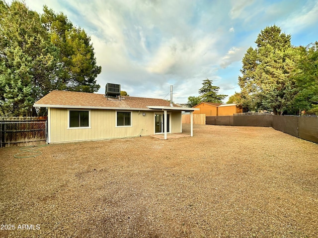 back of property featuring a patio, central AC unit, a fenced backyard, and a shingled roof