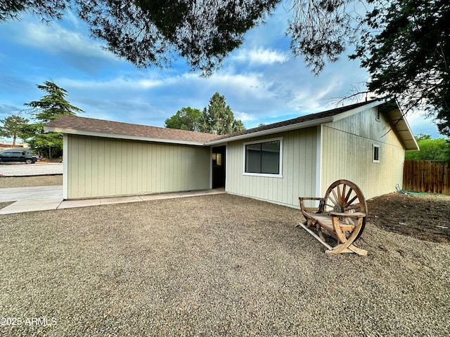 back of property with a shingled roof and fence