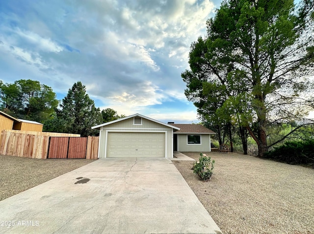 ranch-style house featuring concrete driveway, an attached garage, and fence