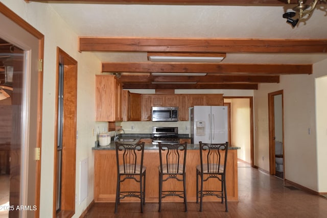 kitchen featuring a sink, stainless steel microwave, white refrigerator with ice dispenser, brown cabinetry, and range