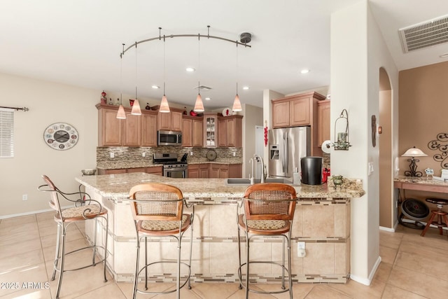 kitchen with a breakfast bar, light stone countertops, and stainless steel appliances