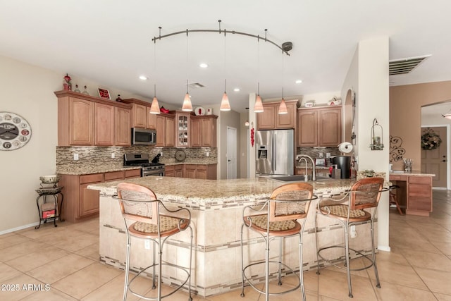 kitchen featuring light stone countertops, sink, stainless steel appliances, a kitchen bar, and light tile patterned floors