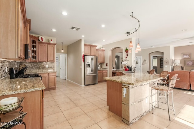 kitchen with hanging light fixtures, sink, appliances with stainless steel finishes, tasteful backsplash, and a kitchen island