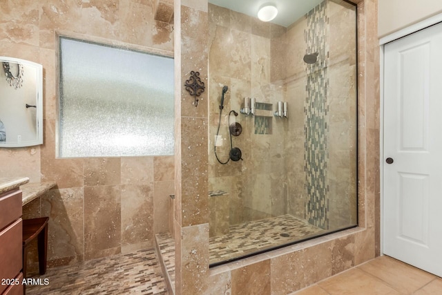 bathroom with tile patterned floors, vanity, and a tile shower