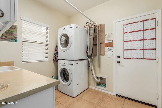 clothes washing area featuring stacked washer / dryer and light tile patterned flooring