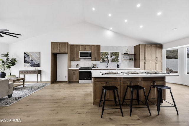 kitchen with appliances with stainless steel finishes, a kitchen breakfast bar, a center island, and sink