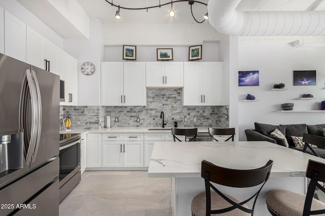 1 E Lexington Ave Unit 1108, Phoenix, AZ 85012 - kitchen featuring appliances with stainless steel finishes, a kitchen breakfast bar, a sink, tasteful backsplash, and white cabinets