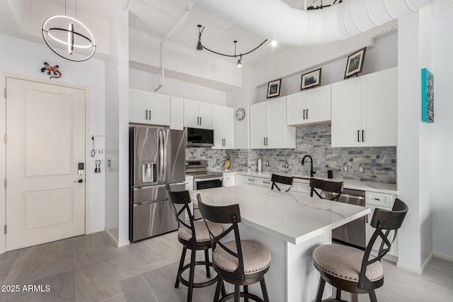 1 E Lexington Ave Unit 1108, Phoenix, AZ 85012 - kitchen featuring stainless steel appliances, a breakfast bar, decorative backsplash, a towering ceiling, and white cabinetry