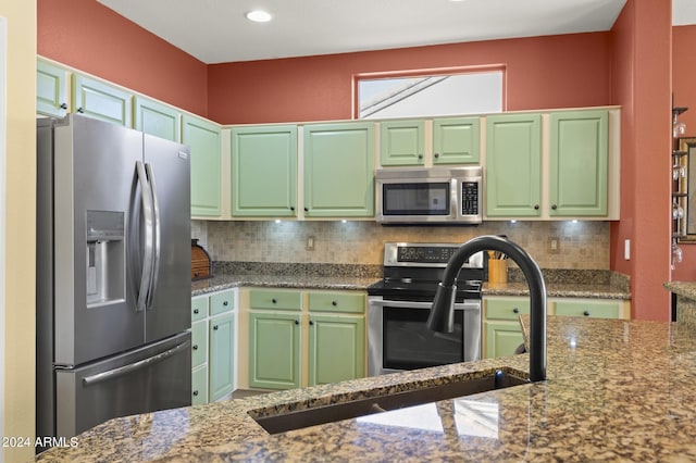 kitchen featuring decorative backsplash, stone counters, appliances with stainless steel finishes, and green cabinetry