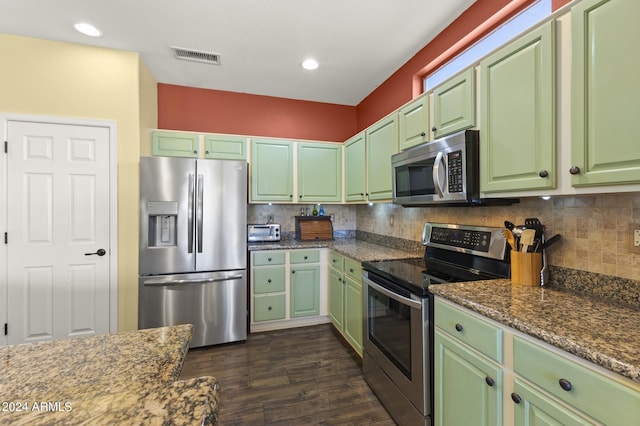 kitchen with decorative backsplash, dark stone countertops, appliances with stainless steel finishes, and dark hardwood / wood-style flooring