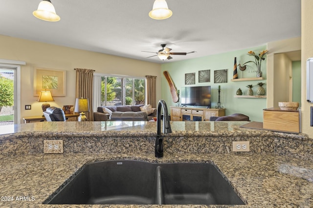 kitchen with ceiling fan, sink, and stone countertops