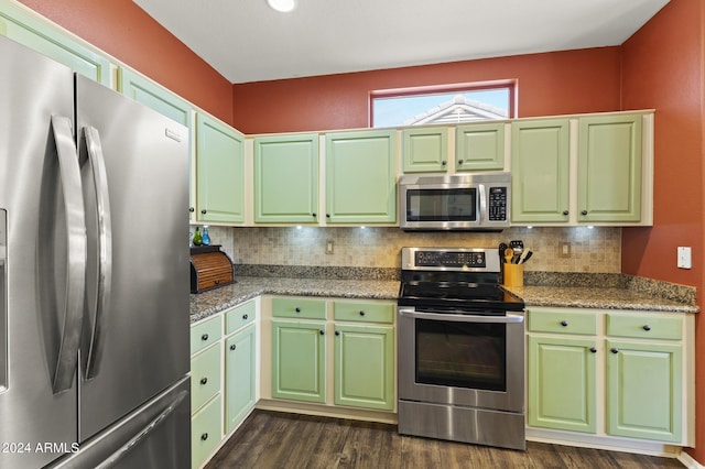 kitchen with light stone countertops, stainless steel appliances, backsplash, and dark wood-type flooring