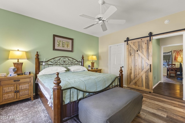 bedroom featuring a barn door, ceiling fan, and dark wood-type flooring