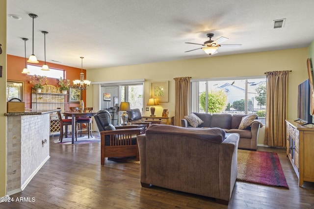 living room featuring a textured ceiling, ceiling fan with notable chandelier, dark hardwood / wood-style floors, and a healthy amount of sunlight