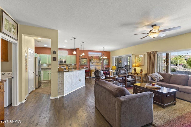 living room featuring ceiling fan with notable chandelier, dark hardwood / wood-style flooring, sink, washer / dryer, and a textured ceiling