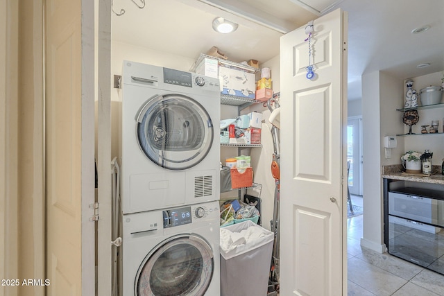 laundry room featuring light tile patterned floors and stacked washer / dryer