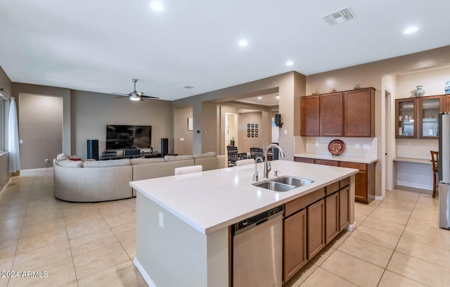 kitchen featuring sink, light tile patterned flooring, stainless steel appliances, and a center island with sink