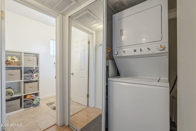 clothes washing area featuring light tile patterned floors and stacked washing maching and dryer