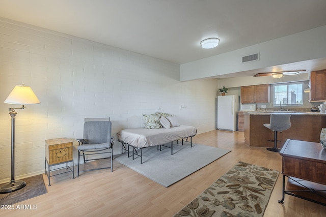 interior space with brick wall, sink, and light wood-type flooring