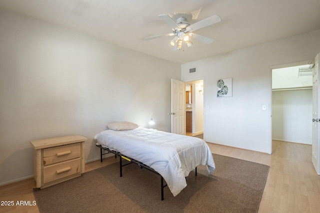 bedroom featuring ceiling fan, a spacious closet, and light hardwood / wood-style floors