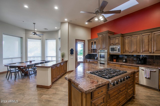 kitchen with backsplash, appliances with stainless steel finishes, dark stone countertops, and a center island