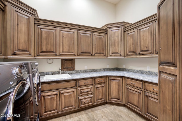 laundry area featuring light hardwood / wood-style floors, cabinets, sink, and washing machine and dryer