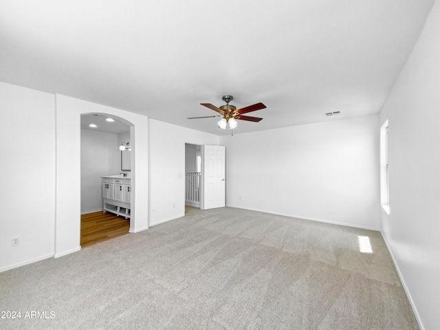 unfurnished bedroom featuring ceiling fan, hardwood / wood-style flooring, and connected bathroom