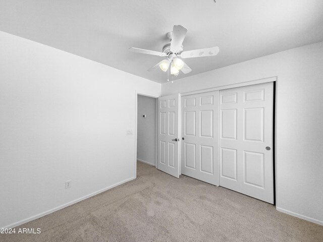 unfurnished bedroom with light colored carpet, a closet, and ceiling fan