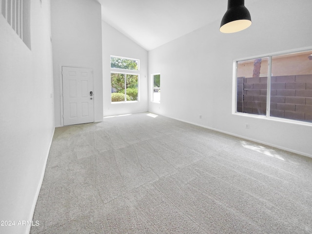 unfurnished living room with light colored carpet and high vaulted ceiling