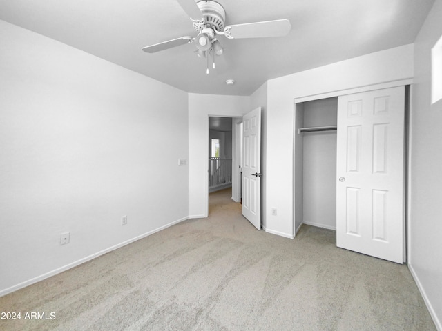 unfurnished bedroom featuring light carpet, ceiling fan, and a closet