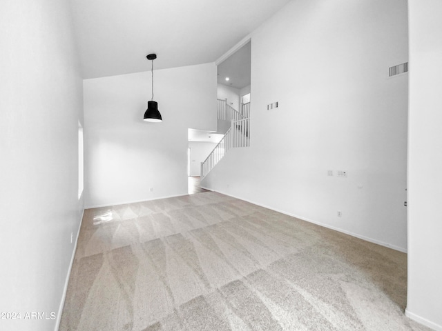 unfurnished living room featuring a towering ceiling and light colored carpet