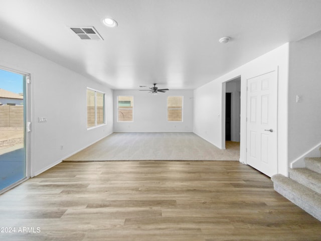 unfurnished living room with light carpet, ceiling fan, and a healthy amount of sunlight