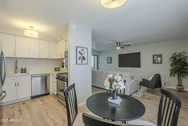 dining area featuring baseboards, a ceiling fan, and light wood-style floors